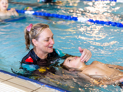 Teacher supporting child floating on back in water