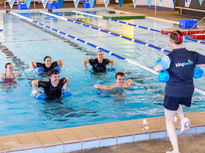 A group of adults lifting weights in the pool during a water aerobics class