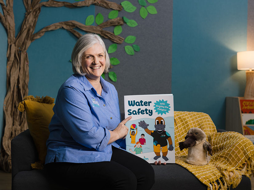 Kingswim staff member smiling holding Kingswim's water safety story book