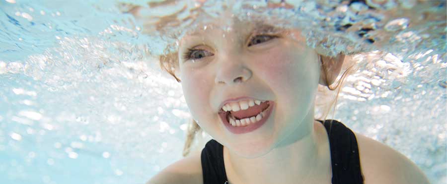 Young toddler smiles while underwater in a pool
