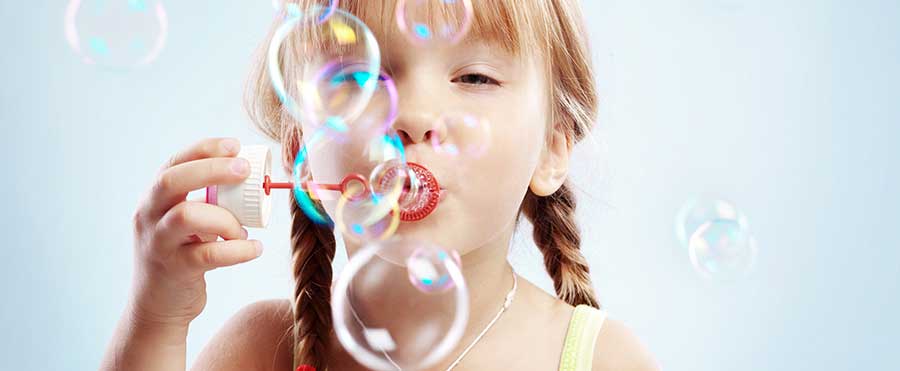 Child with plaits blowing bubbles with a bubble wand