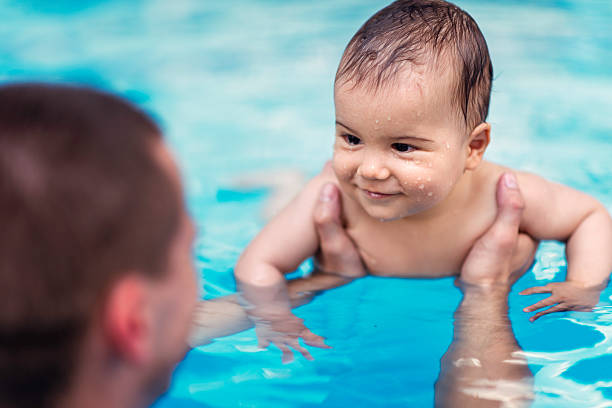 A baby in the swimming pool with his teacher at Kingswim
