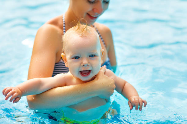A woman holding her baby inside a swimming pool