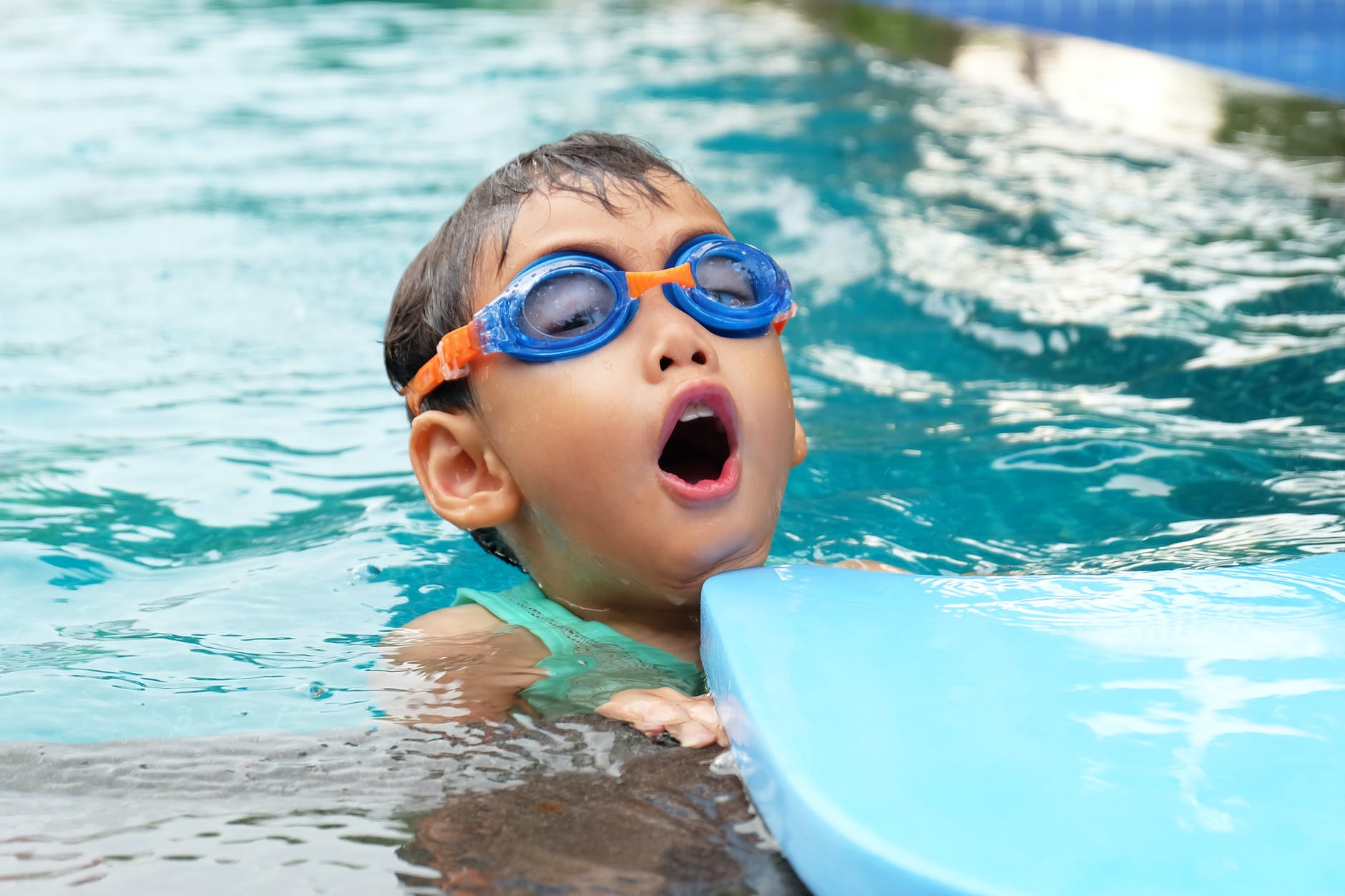 A kid with goggles on learning to swim in the pool